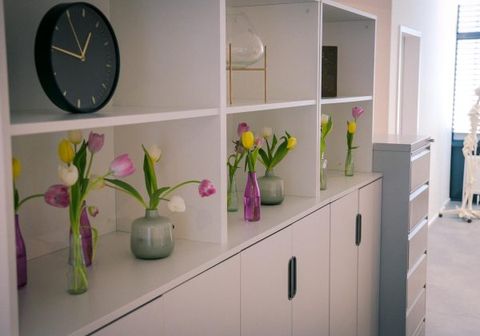 Regal mit Tulpen und Uhr in der Praxis